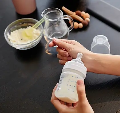 Ibu menyiapkan botol susu dengan standar nutrisi aman untuk bayi.